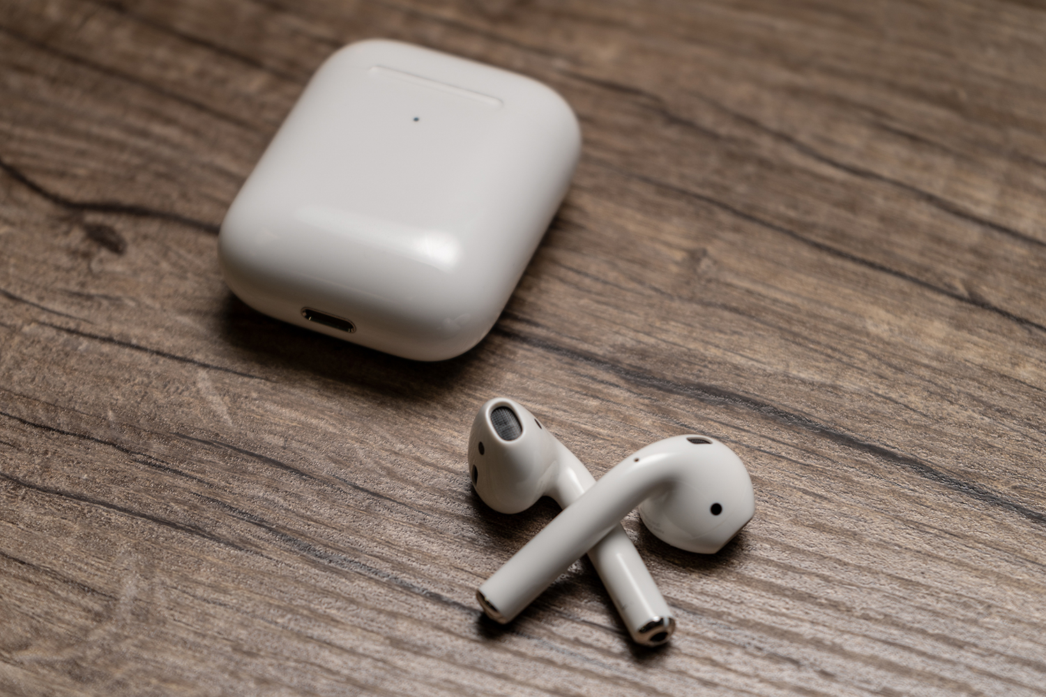 Apple AirPods placed on a table next to their charging case