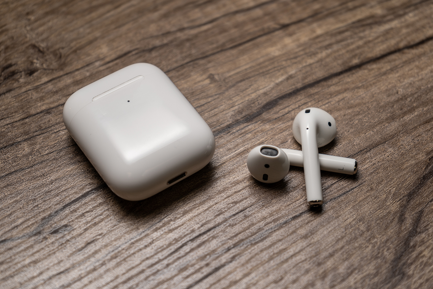 The second-generation Apple AirPods beside their charging case.