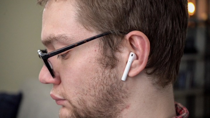 A man wears AirPods 2 seen from his left side.