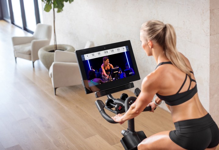 Woman working out with virtual class on an exercise bike. 