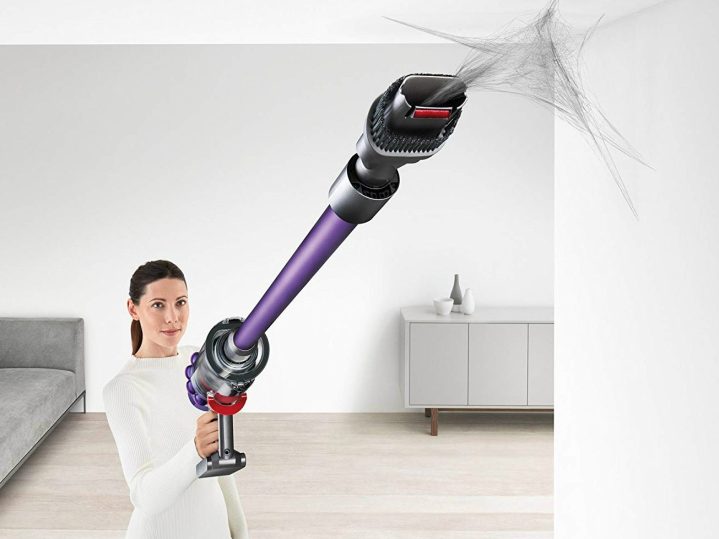 Dyson Cyclone V10 Animal Cordless Stick Vacuum sucks up a cobweb from a ceiling.