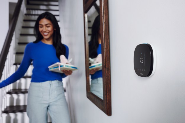 Ecobee smart thermostat installed on wall next to woman walking down stairs.