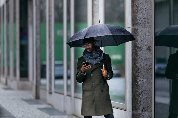 man looking at phone in rain