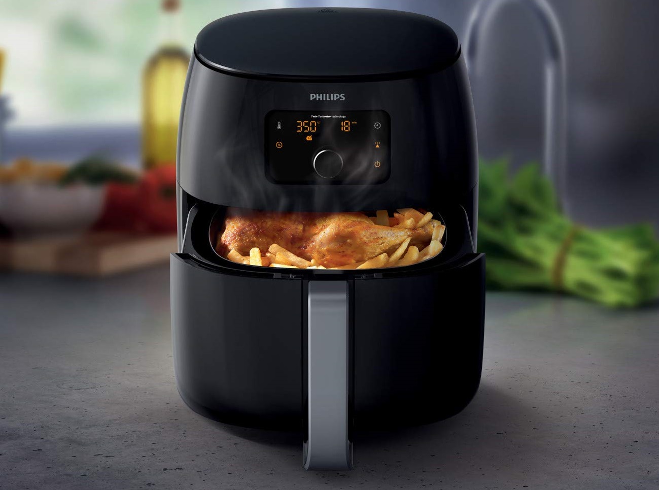 A black Philips Digital Twin TurboStar Air Fryer XXL containing air-fried chicken and french fries.