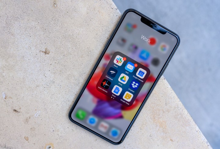 The iPhone 11 Pro Max on concrete with the home screen open and on display.