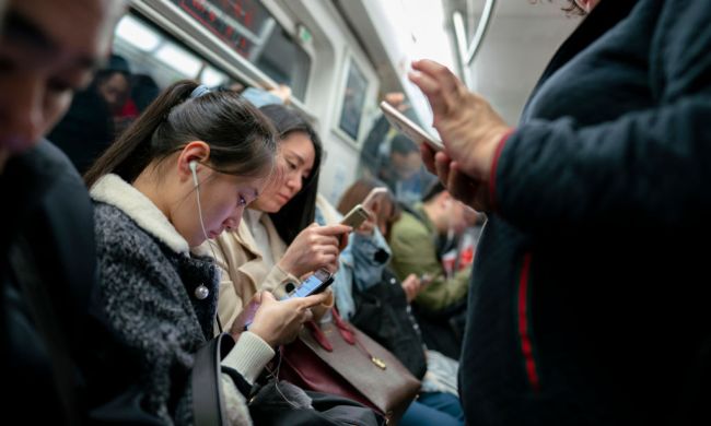 people immersed in using their smartphones on a subway train.