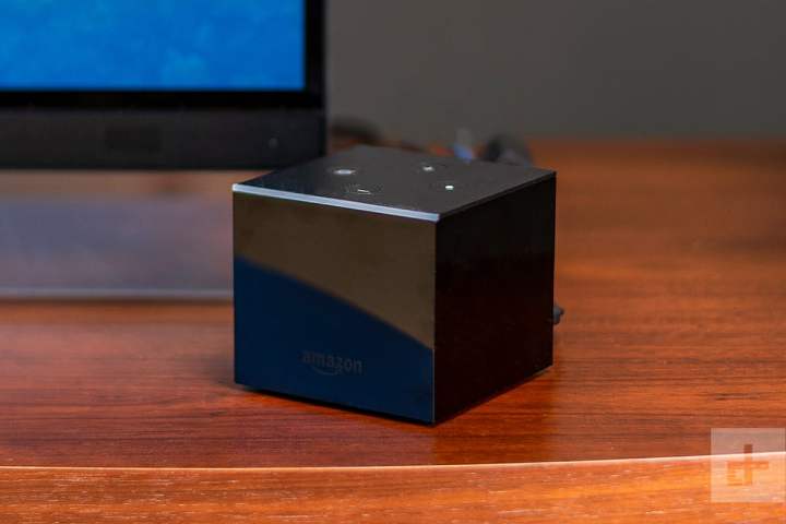 The Amazon Fire TV Cube placed on a counter next to a TV.