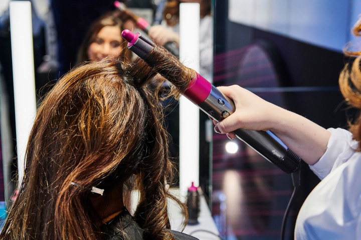 Woman using Dyson Airwrap on another woman's hair.