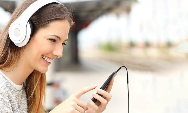 Woman listening to music on her smartphone via a headphone adapter.