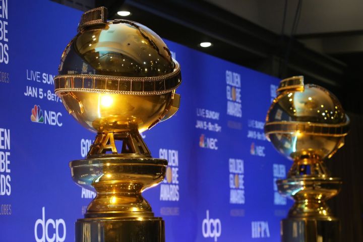 Two golden globes trophies on the red carpet.