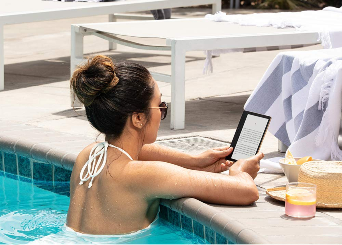 Uma mulher lendo um e-book no Amazon Kindle Oasis enquanto está em uma piscina.