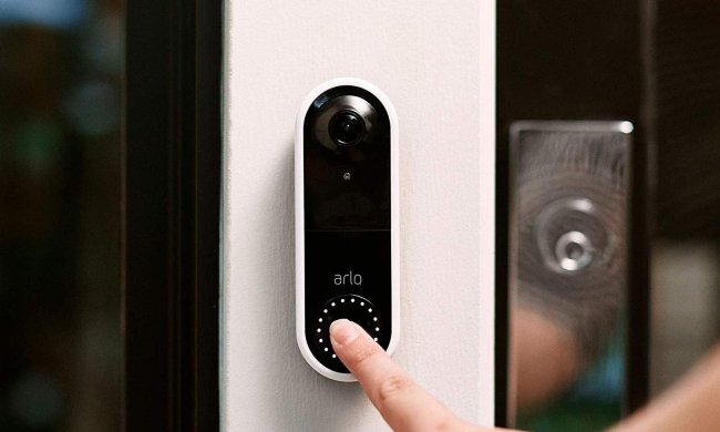 A person pressing the Arlo Video Doorbell.