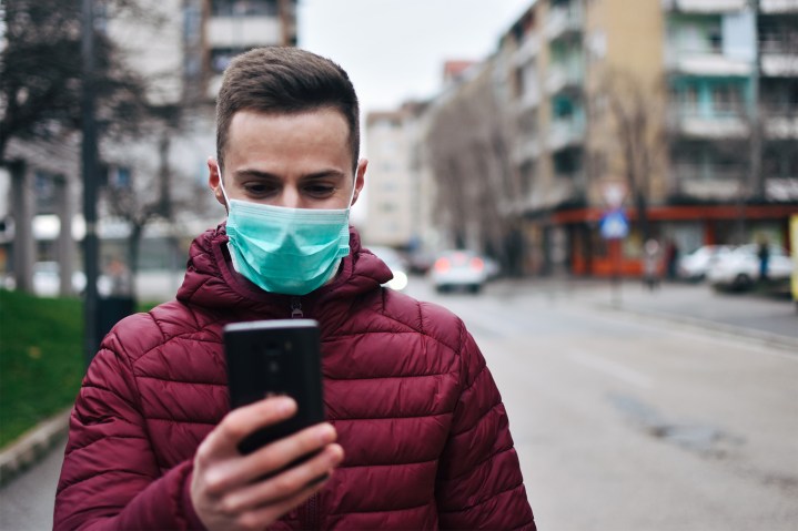 man checking phone with mask on