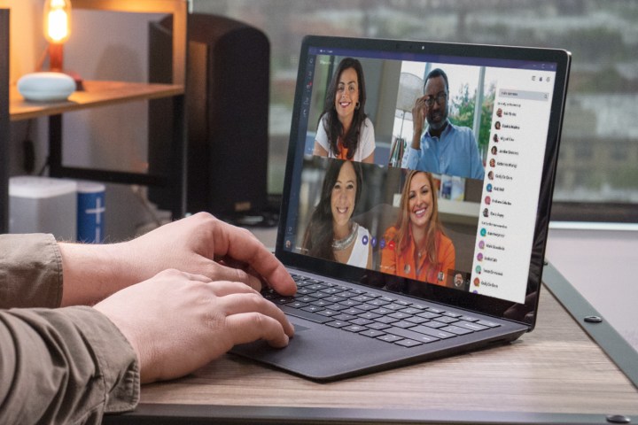 Close up of a person's hands on a laptop keyboard as the person attends a group video call. 