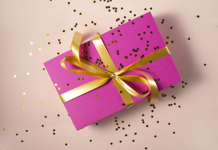 Festively wrapped package with gold ribbon and confetti. 