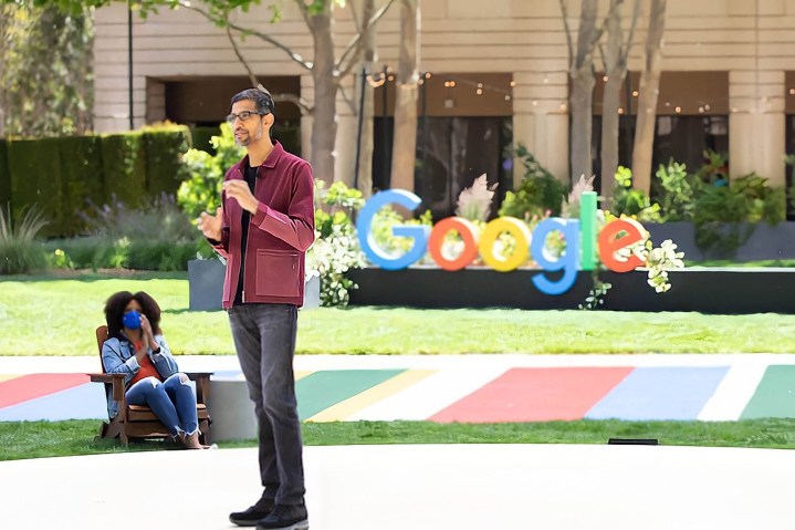 Sundar Pichai stands in front of a Google logo at Google I/O 2021.