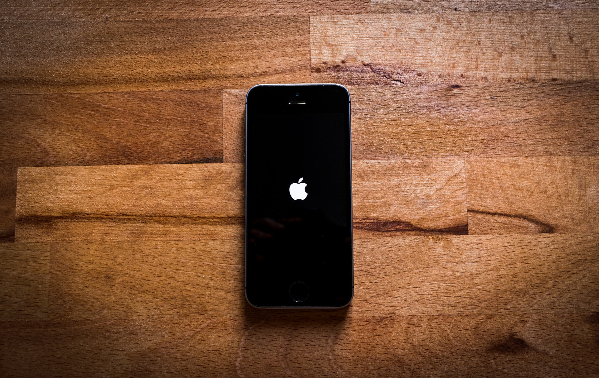 An iPhone powering up on a wooden table.
