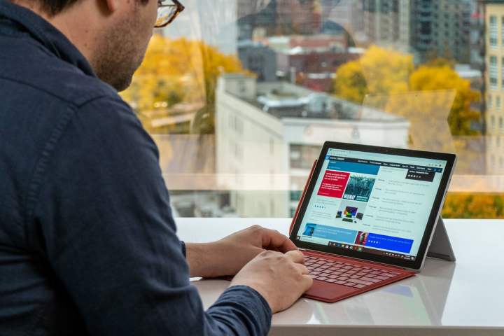 A person typing on a Surface Pro 7 with a red Type Cover.