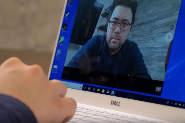 Gros plan d'une personne utilisant un ordinateur portable Dell avec sa webcam allumée. L'image de la personne est affichée sur l'écran de l'ordinateur portable.