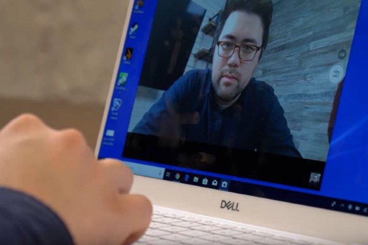 Close up of a person using a Dell laptop with their webcam turned on. The person's image is shown on the laptop screen.