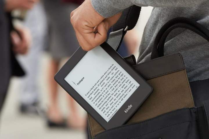 A close up of someone pulling a Kindle out of their bag.