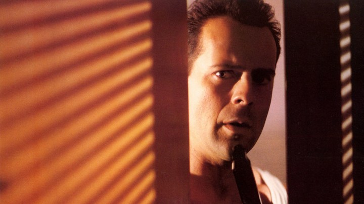 John McClane espiando por trás de uma parede em Die Hard