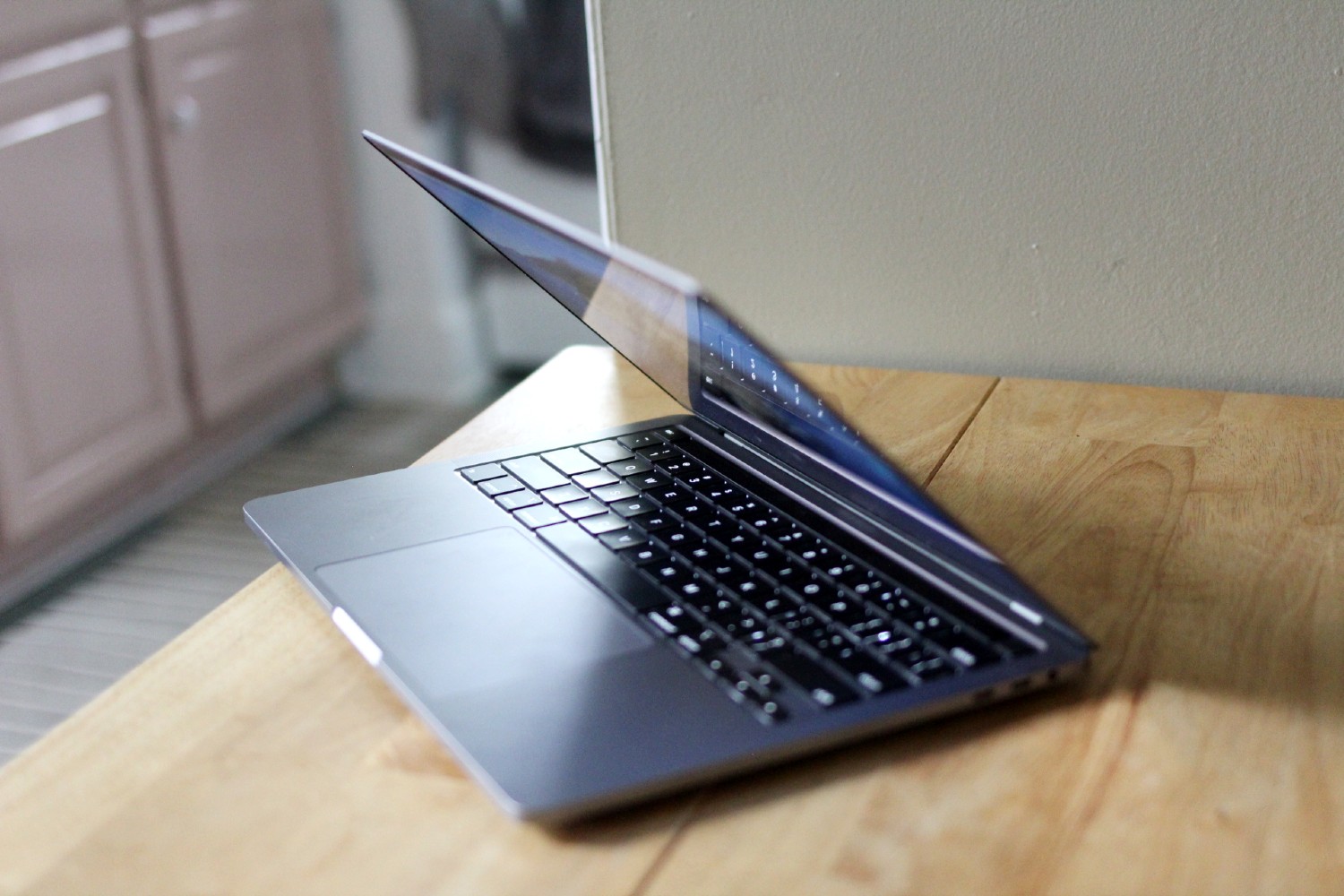 Um MacBook Pro de 13 polegadas está parcialmente aberto sobre uma mesa.