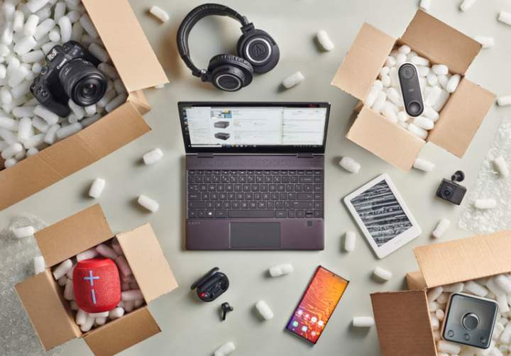 Open boxes revealing a variety of tech purchases, including a camera, tablet, smart speaker, laptop, headphones, and more. 
