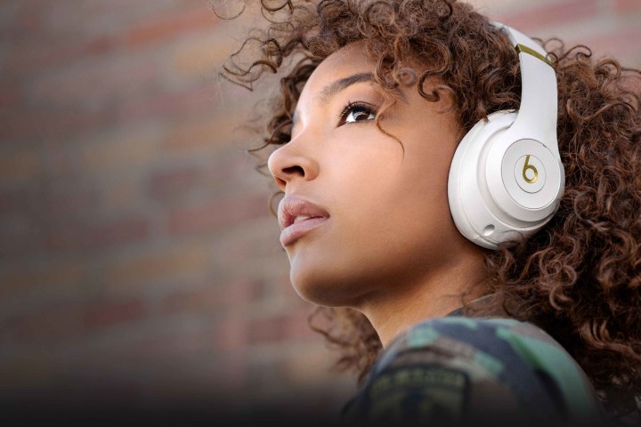 A woman wears the white version of the Beats Studio 3 wireless headphones.