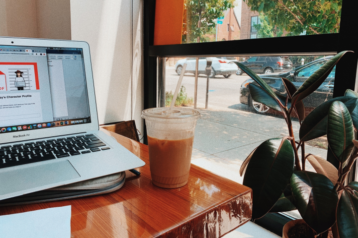 Persona sentada con la computadora en la cafetería con café helado