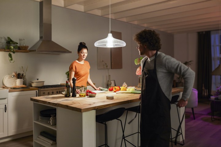 Two people standing in a kitchen lit by a Philips Hue light.