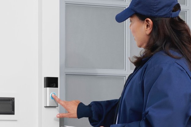 The Ring Video Doorbell on a door frame while a woman touches it.