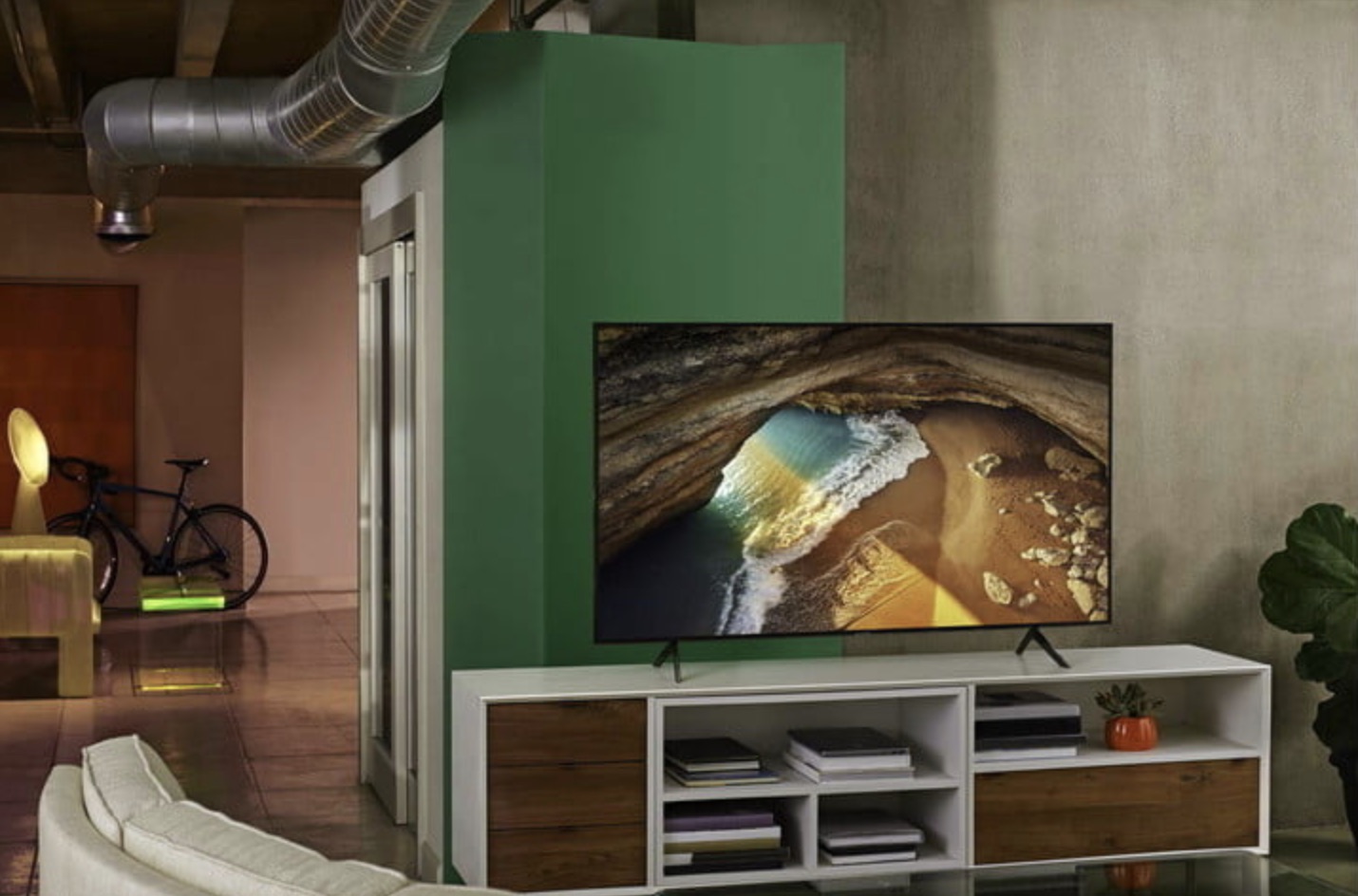 The Samsung Q70A 4K TV on a media console in a modern loft-style dwelling.