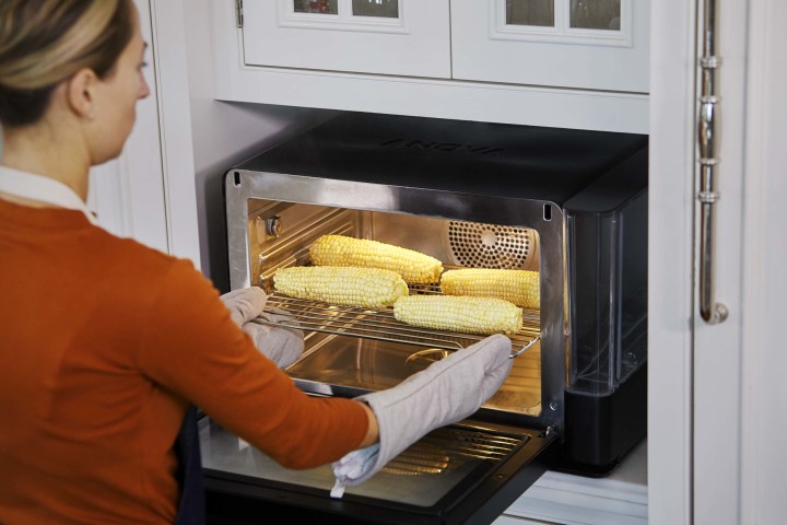 A woman cooking corn in a smart oven.