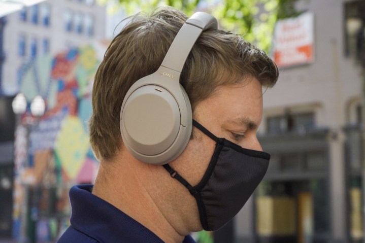 Un uomo con una maschera che indossa le cuffie Sony WH 1000XM4.