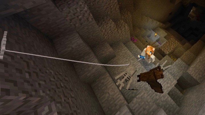 A minecraft character uses a grappling hook to climb out of the underground.