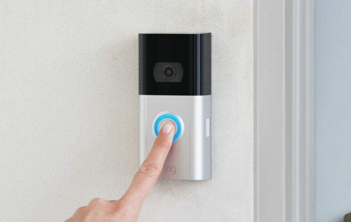 A person pressing the button of the Ring Video Doorbell 3.