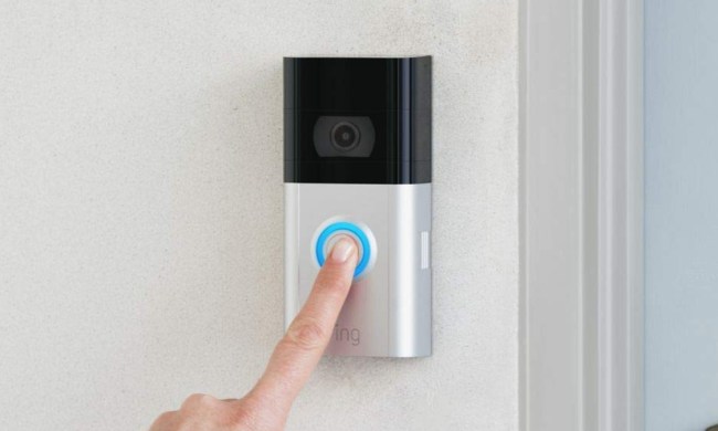 A person pressing the button of the Ring Video Doorbell 3.