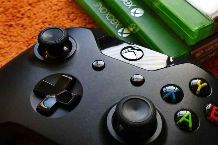 Un controller Xbox si trova su un pavimento accanto a una pila di giochi Xbox One.