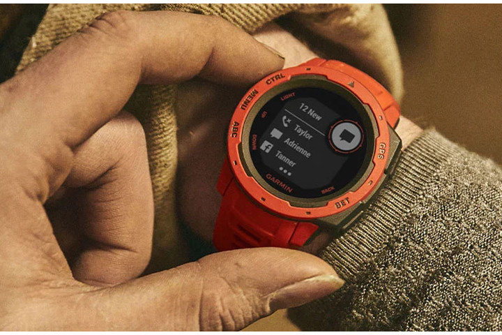 Um smartwatch Garmin Instinct laranja sendo mostrado em um pulso.