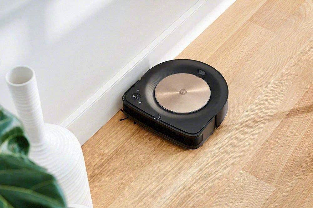 O robô iRobot Roomba S9 Plus aspira o chão perto da parede.