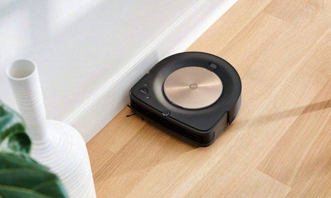 The iRobot Roomba S9 Plus robot vacuum cleaning the floor near the wall.