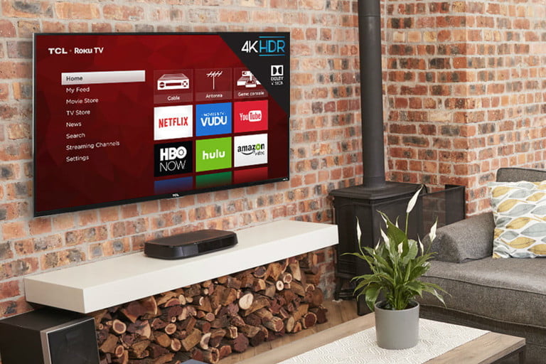 Uma TV 4K TCL 4 Series é montada em uma parede de tijolos em uma sala de estar.