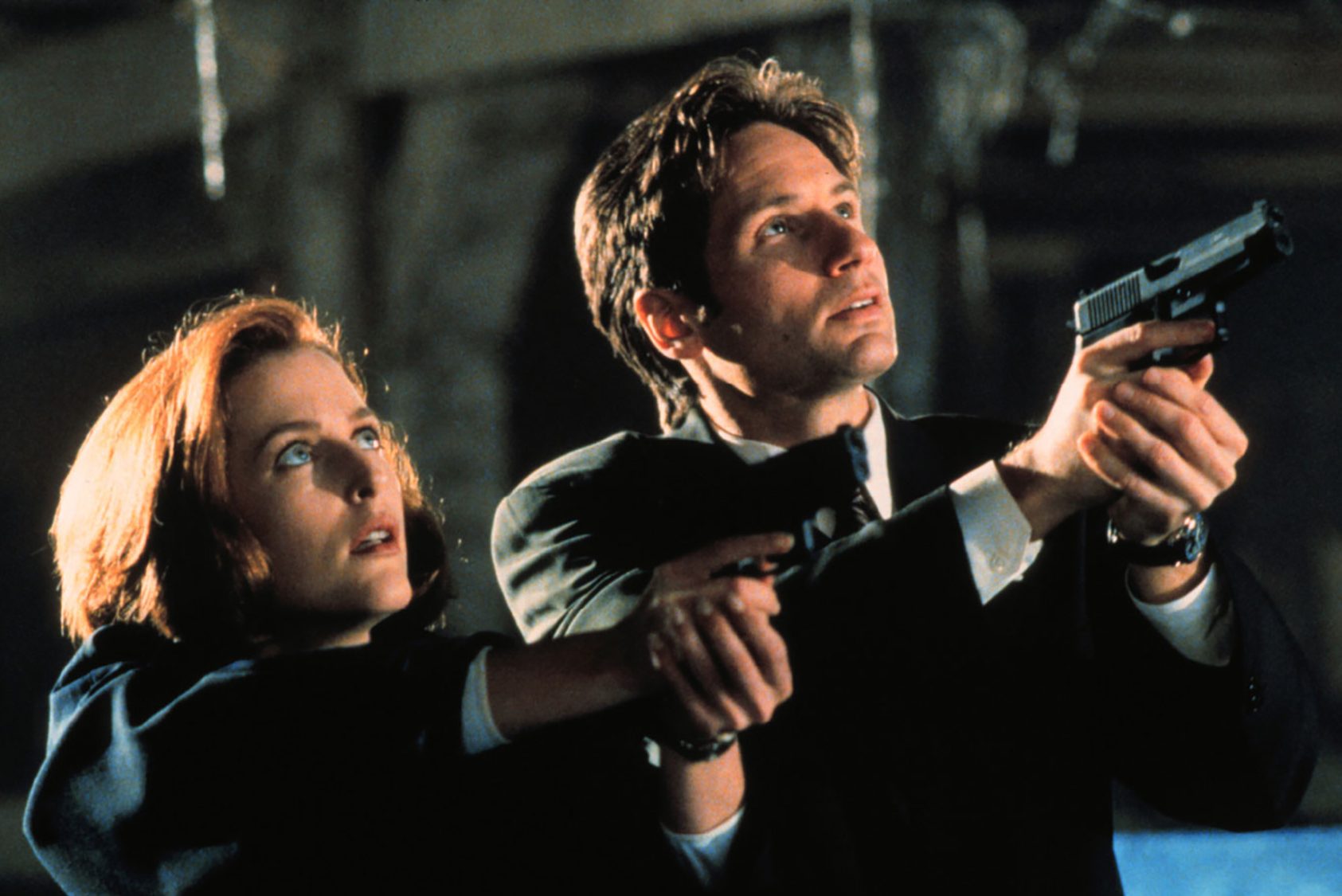 یک مرد و یک زن در The X-Files اسلحه به دست می گیرند.