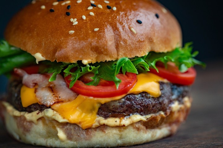 Primer plano de una hamburguesa con queso con lechuga y tomate.