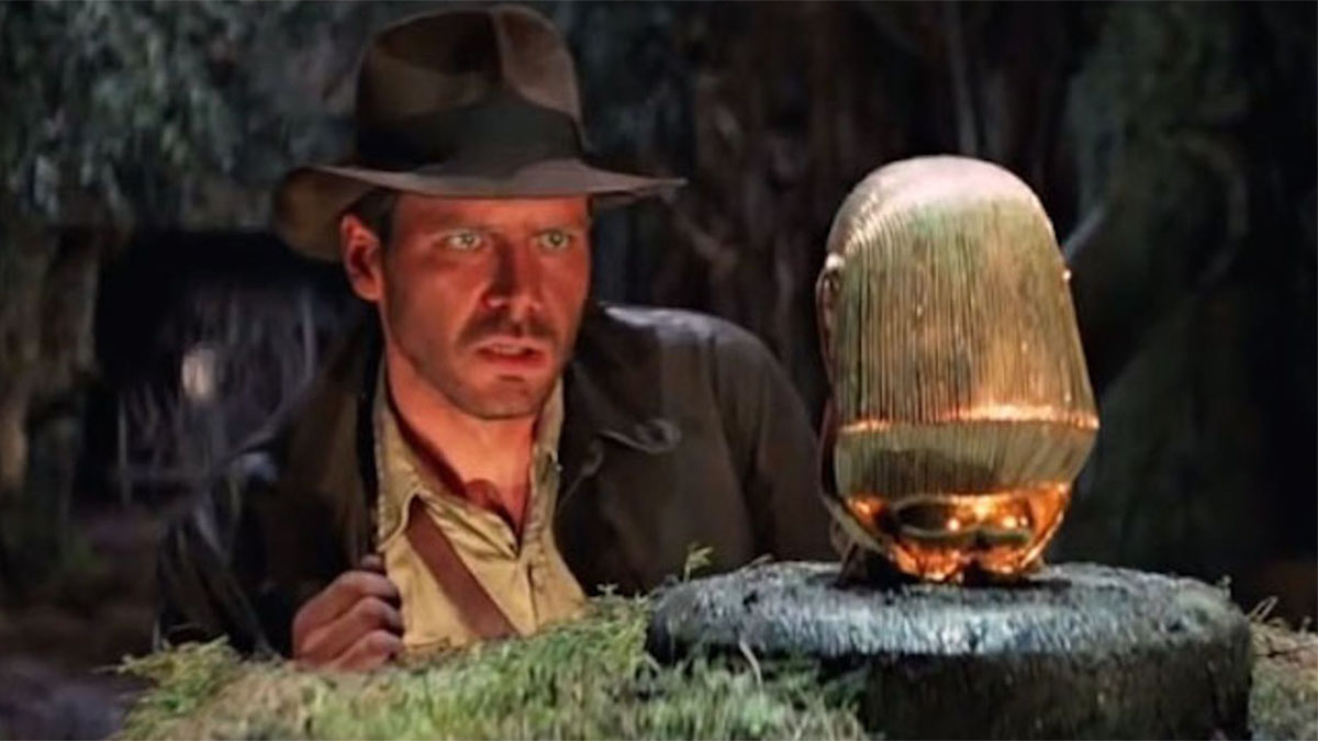 Indiana Jones olhando para um ídolo de ouro em "Os Caçadores da Arca Perdida".