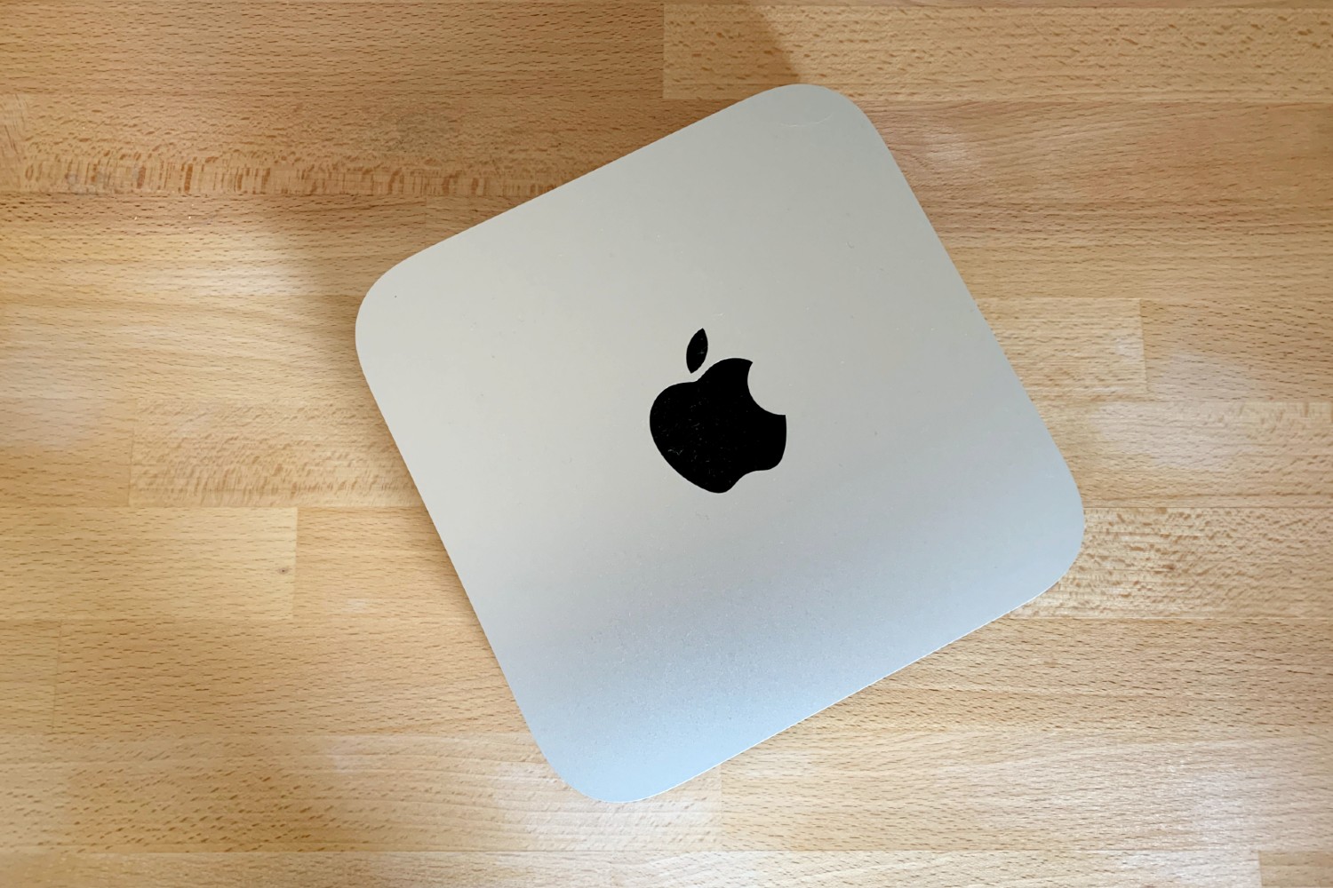 The 2020 Mac Mini, powered by Apple's M1 chip, on a wooden surface.