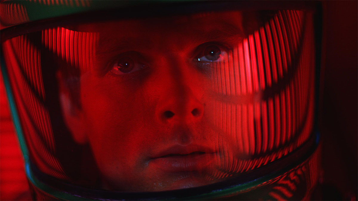 Un primer plano de un astronatu con una luz roja reflejándose en su casco en la película 2001: Una odisea del espacio.