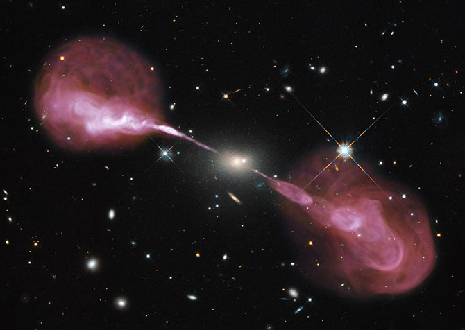 The radio galaxy Hercules A has an active supermassive black hole at its centre. Here it is pictured emitting high energy particles in jets expanding out into radio lobes.