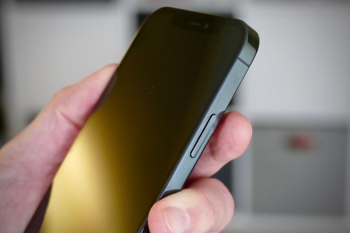 Person holding powered off iPhone 12 Pro with side button showing.